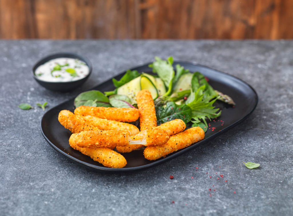Golden crispy breaded mozzarella sticks served with a dipping sauce and fresh salad: a high-yield snack format for professional foodservice appetizer menus.
