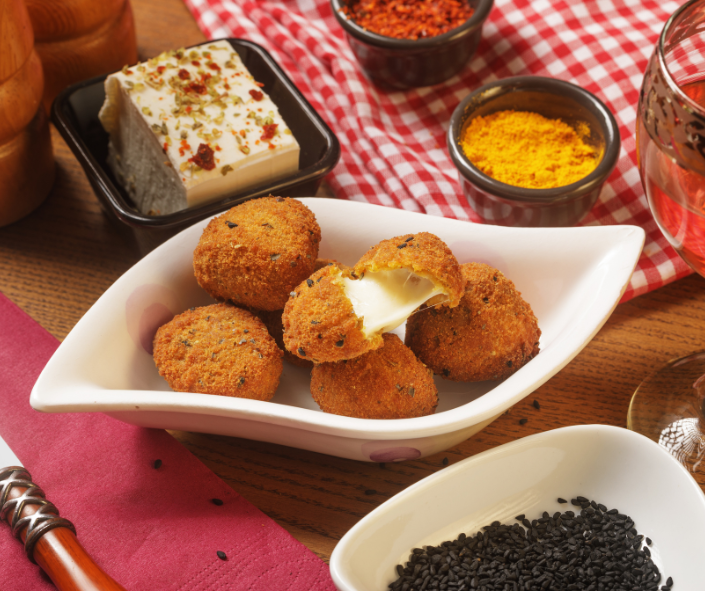 Crispy breaded mozzarella croquettes with a melted Maestrella mozzarella center, served with spices and seasonings for a versatile appetizer or sharing platter in professional foodservice.