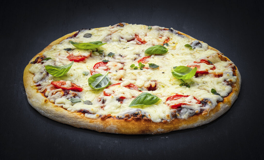 Margherita-style pizza with Maestrella grated mozzarella, fresh tomatoes and basil — consistent melt and golden finish for professional foodservice operations.