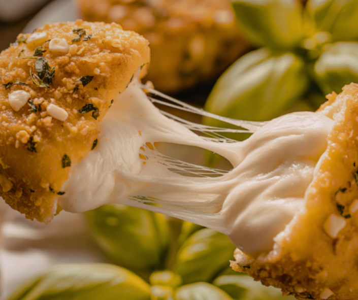 Close-up of a breaded mozzarella croquette pulled apart revealing a long, stretchy Maestrella mozzarella melt, showcasing superior cheese performance for professional foodservice menus.
